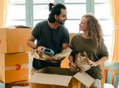 multiethnic couple packing ceramic belongings in parchment before relocation